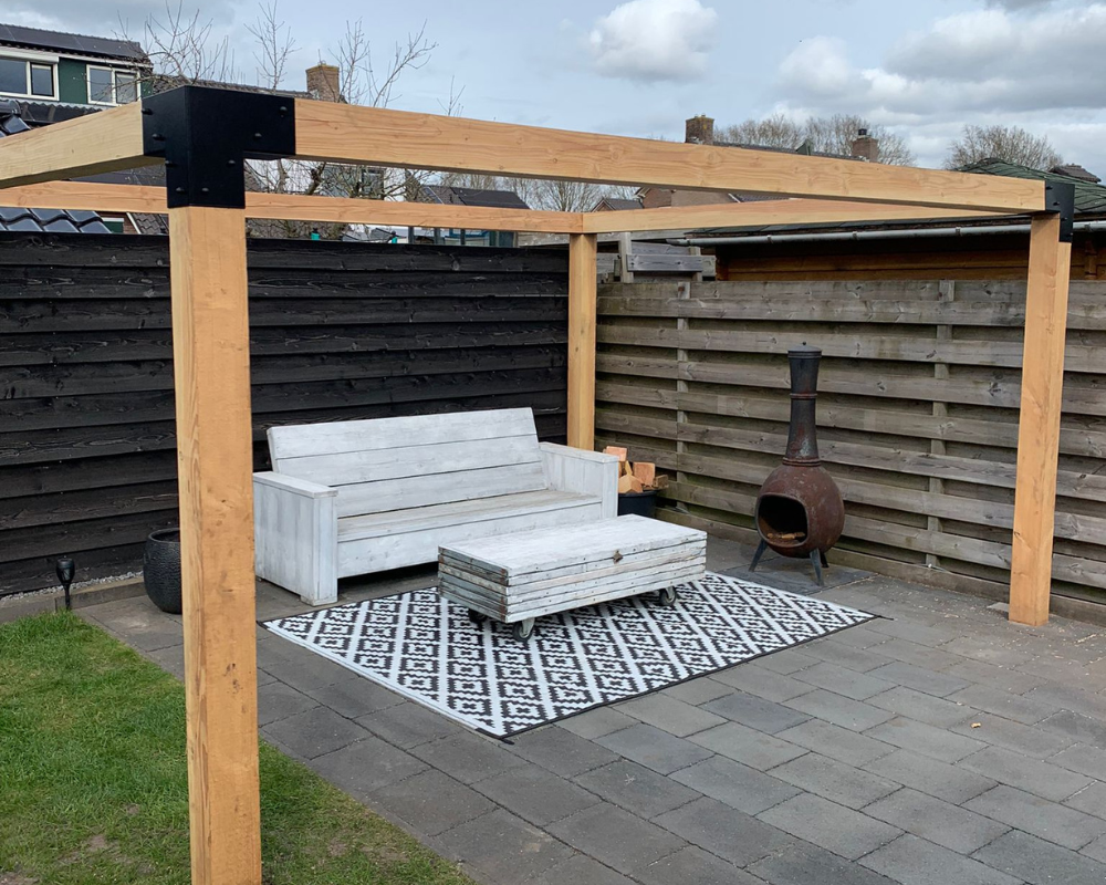 Houten pergola met zwarte metalen koppelstukken in een moderne tuin. Robuuste Douglas constructie als basis voor een overkapping of schaduwdoek.