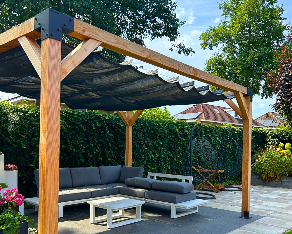 Houten pergola van Douglas hout (12x12 cm) met zwart harmonicadoek. Luxe terrasoverkapping met stevige metalen koppelstukken, ideaal voor een sfeervolle loungeplek in de tuin.