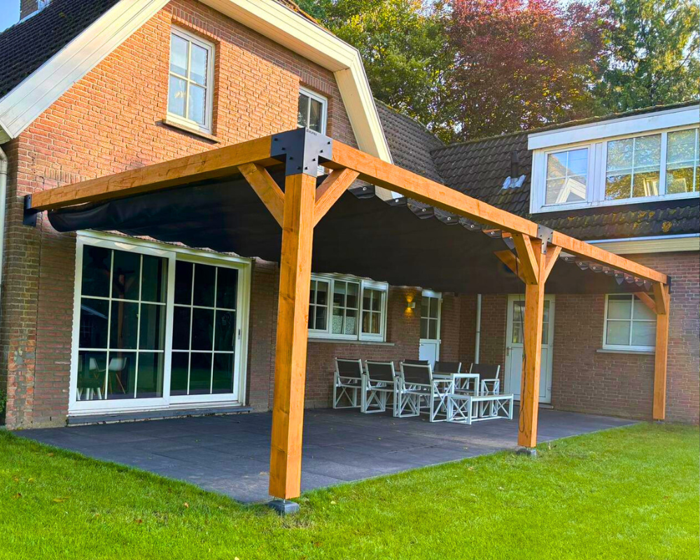 Dubbele houten pergola met harmonicadoek tegen een gevel. terrasoverkapping van Douglas hout met 15x15cm palen en stevige metalen koppelstukken.