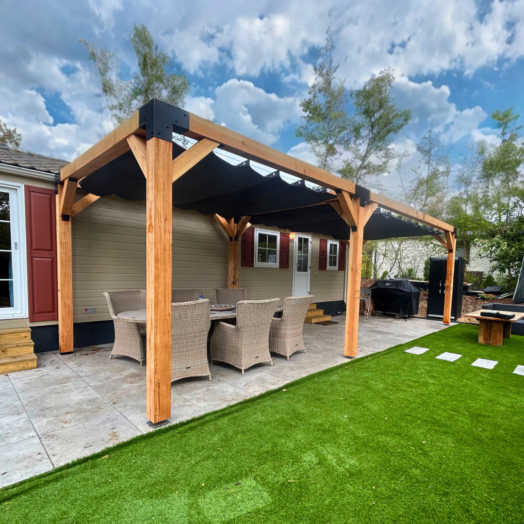 Dubbele houten pergola met zwart harmonicadoek aan een chalet. Luxe terrasoverkapping van Douglas hout met stevige metalen koppelstukken, ideaal voor een sfeervolle zonwering buitenruimte 